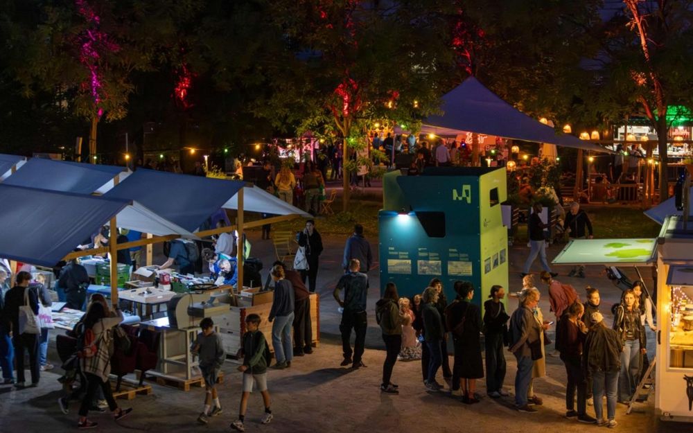 Abendliche Szene eines belebten Sommerfests mit Marktständen, Lichtern und zahlreichen Besucherinnen und Besuchern im Museumsgarten.