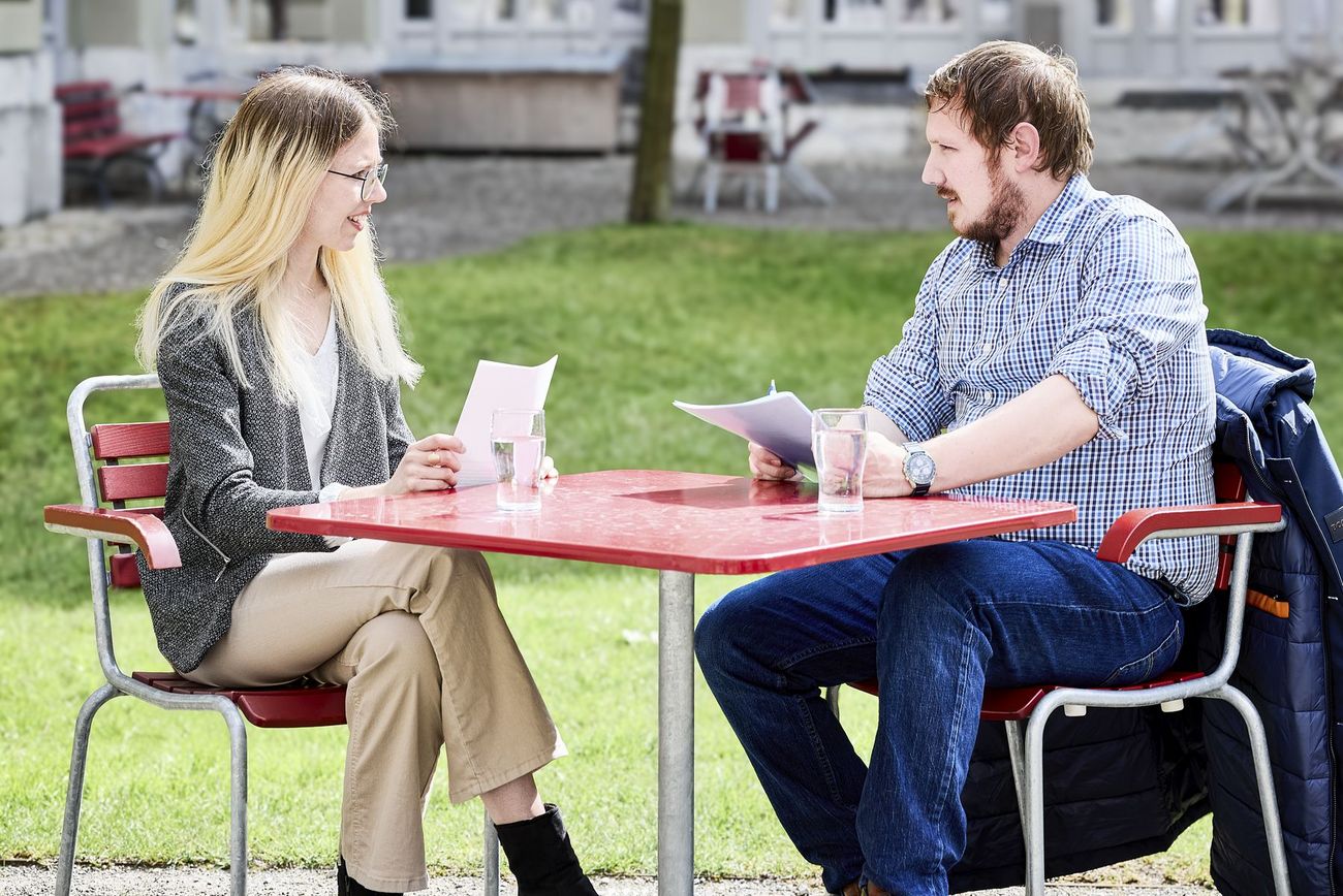 Zwei Personen sitzen zusammen an einem Tisch im Gespräch