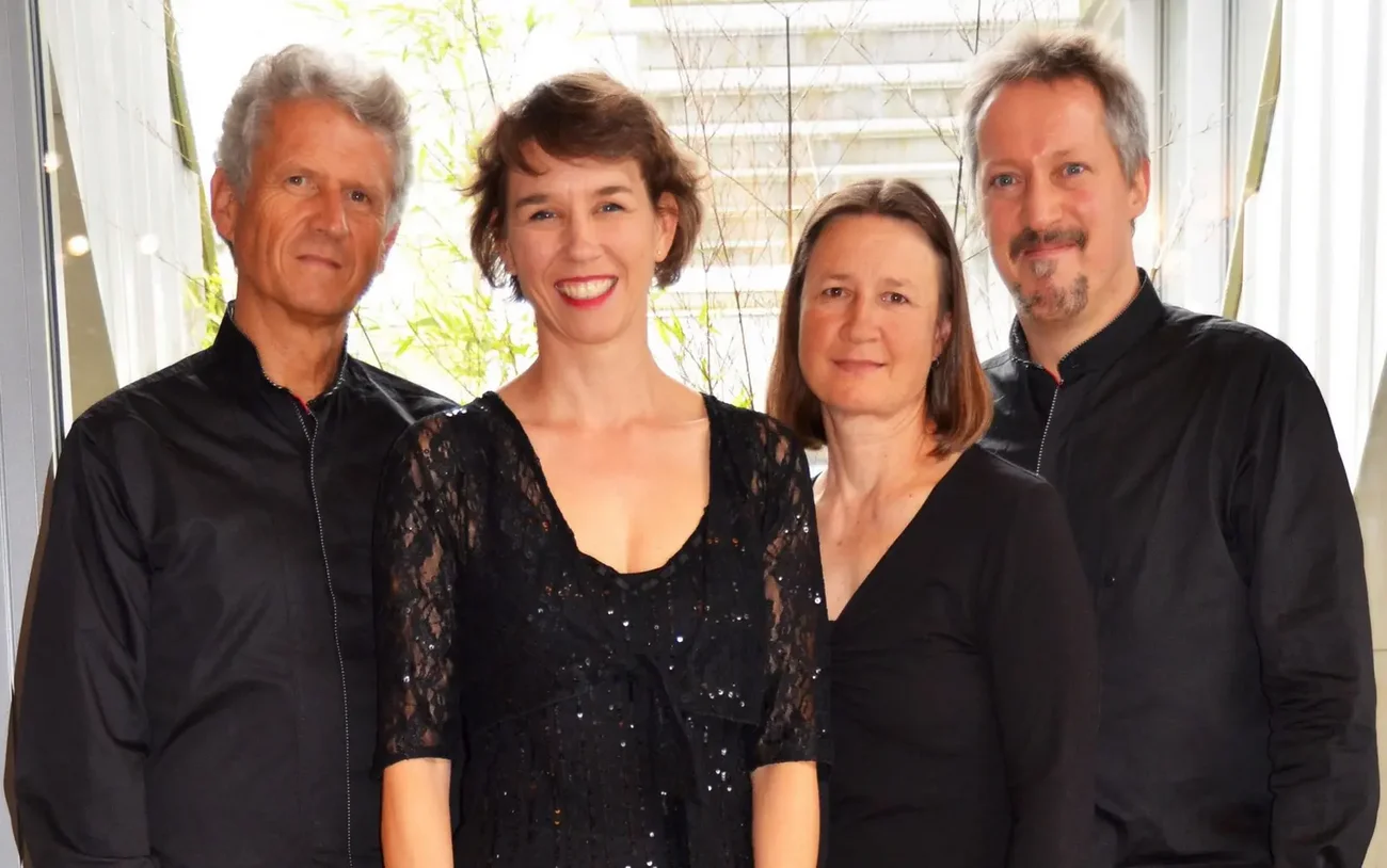 Vier Personen des Quartetts COLLA PARTE stehen nebeneinander in schwarzer Konzertkleidung und blicken in die Kamera, im Hintergrund ein heller Innenraum mit Pflanzen.