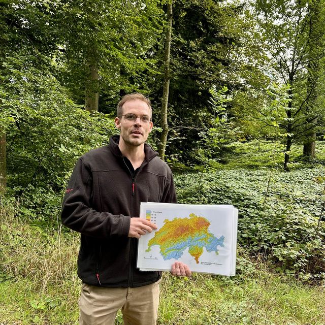 Philipp Egloff hält eine Klimakarte der Schweiz