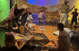 Kinder spielen kreativ mit Folien und Materialien im Raum.