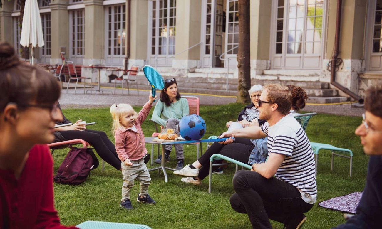 Menschen unterschiedlichen Alters spielen und sitzen zusammen im Innenhof.