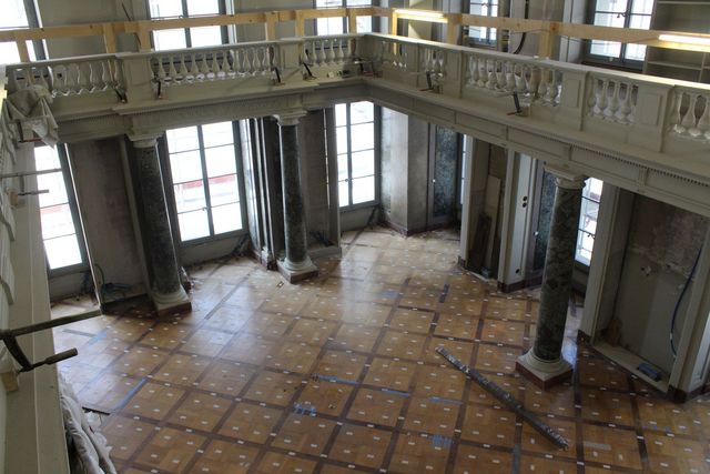 Grosser, leerer Saal im Umbau mit hohen Fenstern und Säulen.
