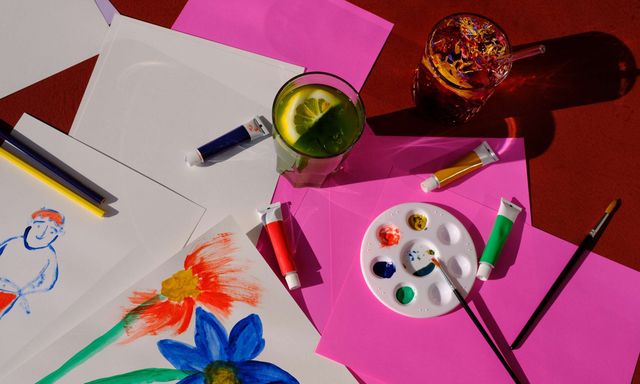 Maltisch mit Farben, Zeichnungen und Getränken.
