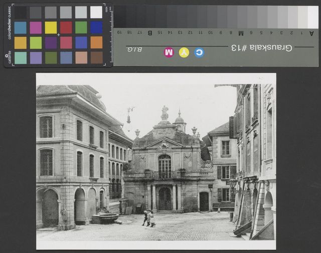 Schwarz-weiss Bild aus einer Strasse mit Altstadtgebäuden links, rechts und im Hintergrund