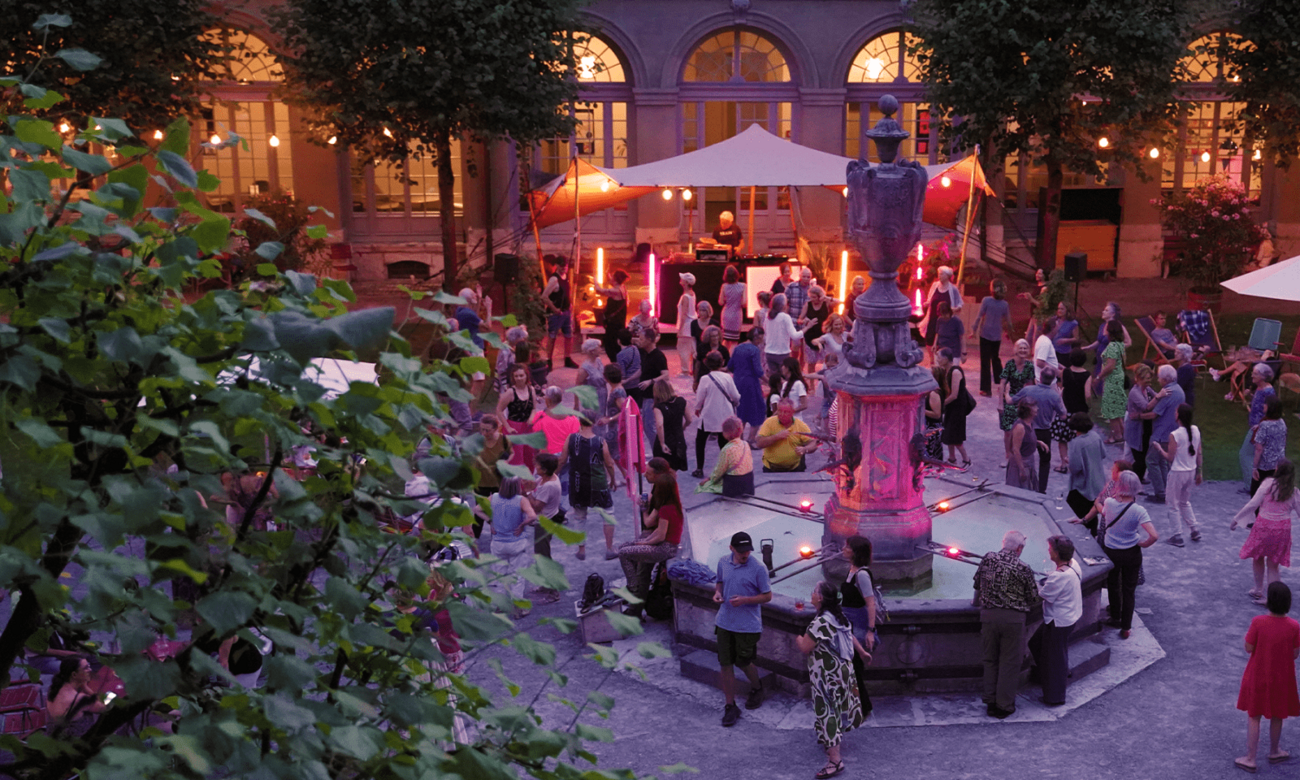 Tanzende Menschen im beleuchteten Innenhof bei Abendveranstaltung.