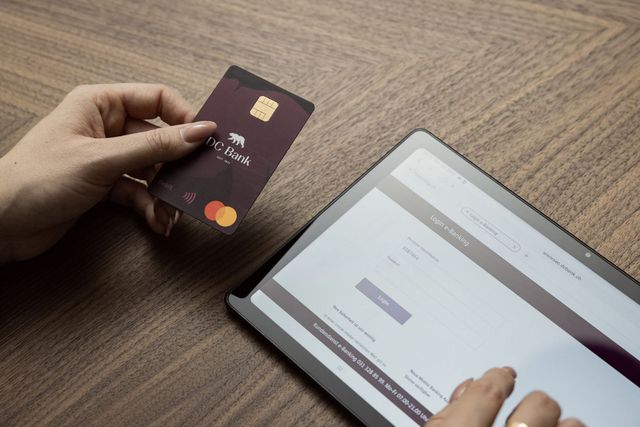 Hände mit Kreditkarte der DC Bank und Tablet