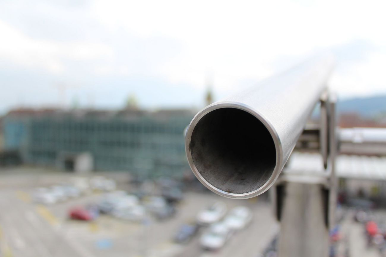 Nahaufnahme eines Metallrohrs mit unscharfem Stadtblick im Hintergrund.
