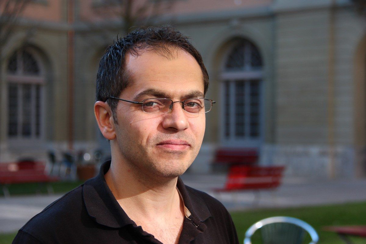 Portrait eines Mannes mit dunklen Haaren und einer Brille, welcher im Innenhof des Burgerspitals steht..