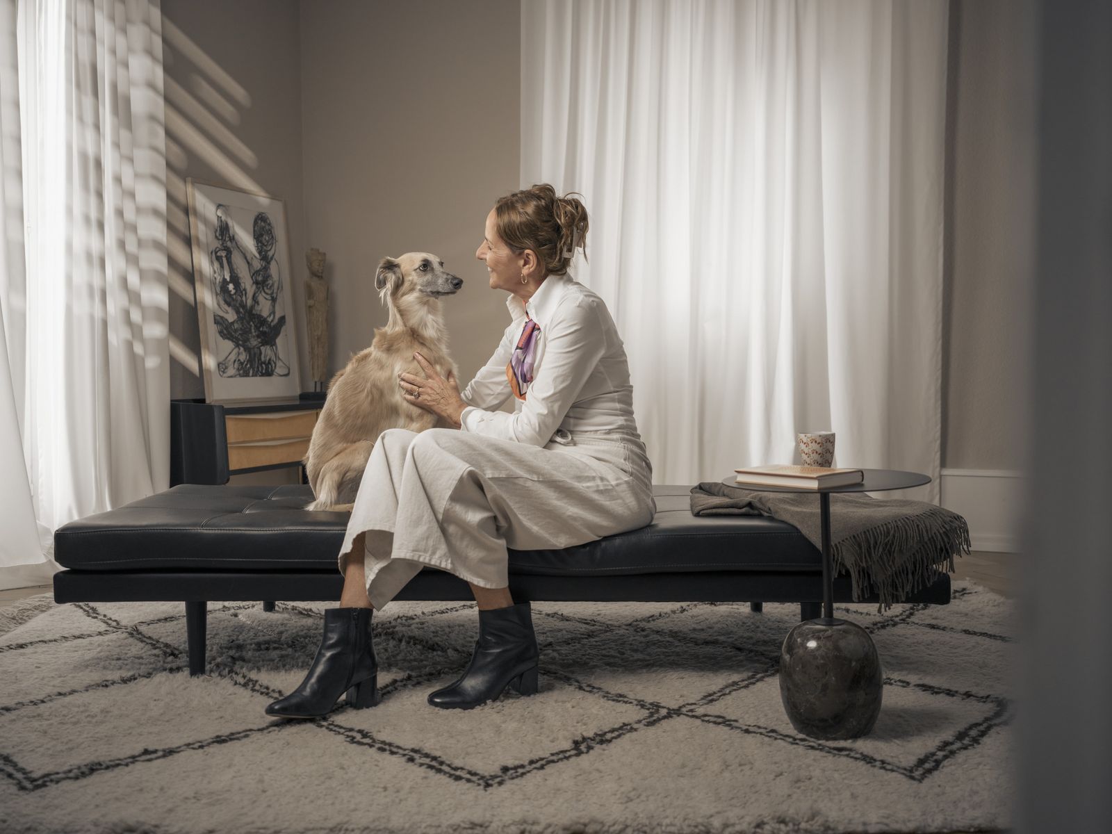 Frau sitzt mit ihrem Hund auf einer Couch