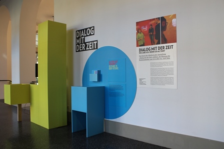 Ausstellungswand im Berner Generationenhaus mit farbigen Informationsmodulen und dem Titel Dialog mit der Zeit.
