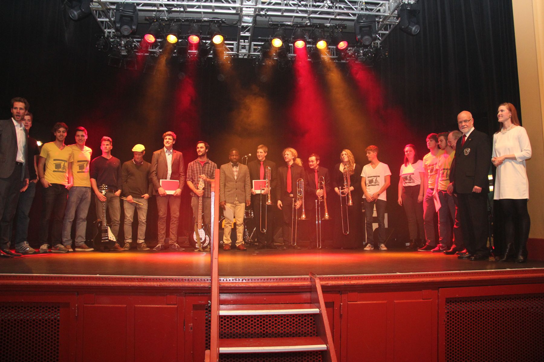 Reihe von Menschen auf einer Bühne mit farbiger Beleuchtung.