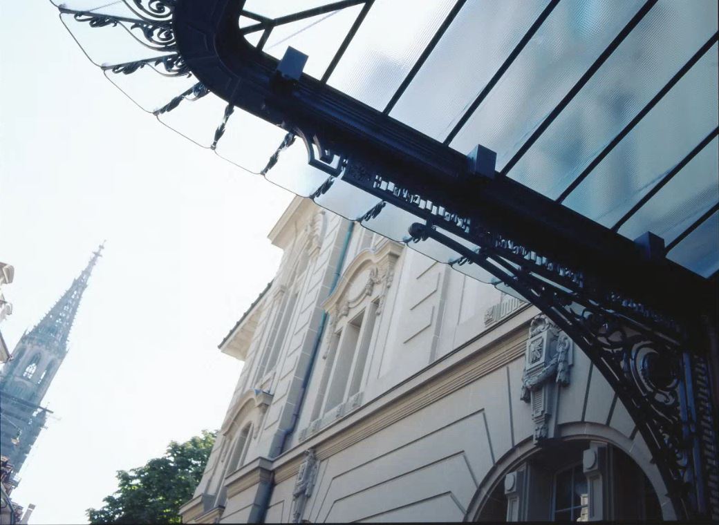 Fassade des Kultur Casinos Bern unter einem verzierten Glasdach, im Hintergrund ist das Berner Münster ersichtlich..