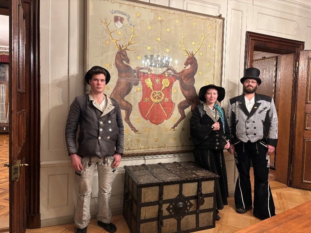 Mitglieder der Zunf zu Pfistern vor ihrem Wappen