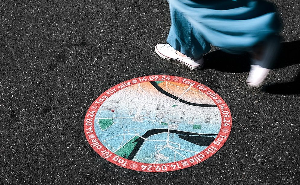 Stadtplan mit Programm am Boden, man sieht Füsse beim vorbeilaufen