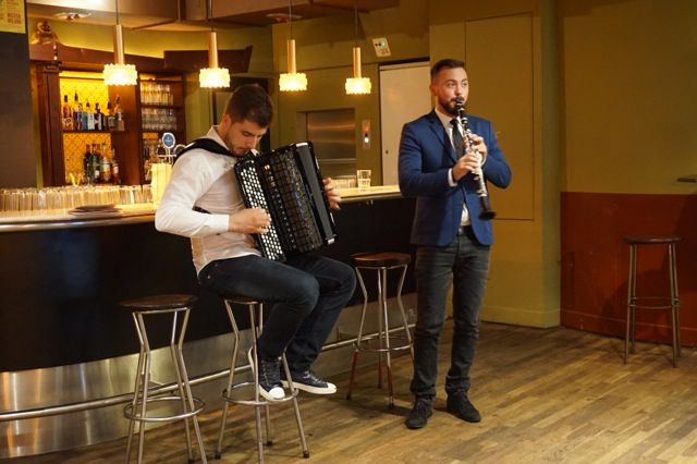 Zwei Musiker spielen Akkordeon und Klarinette in einer Bar.
